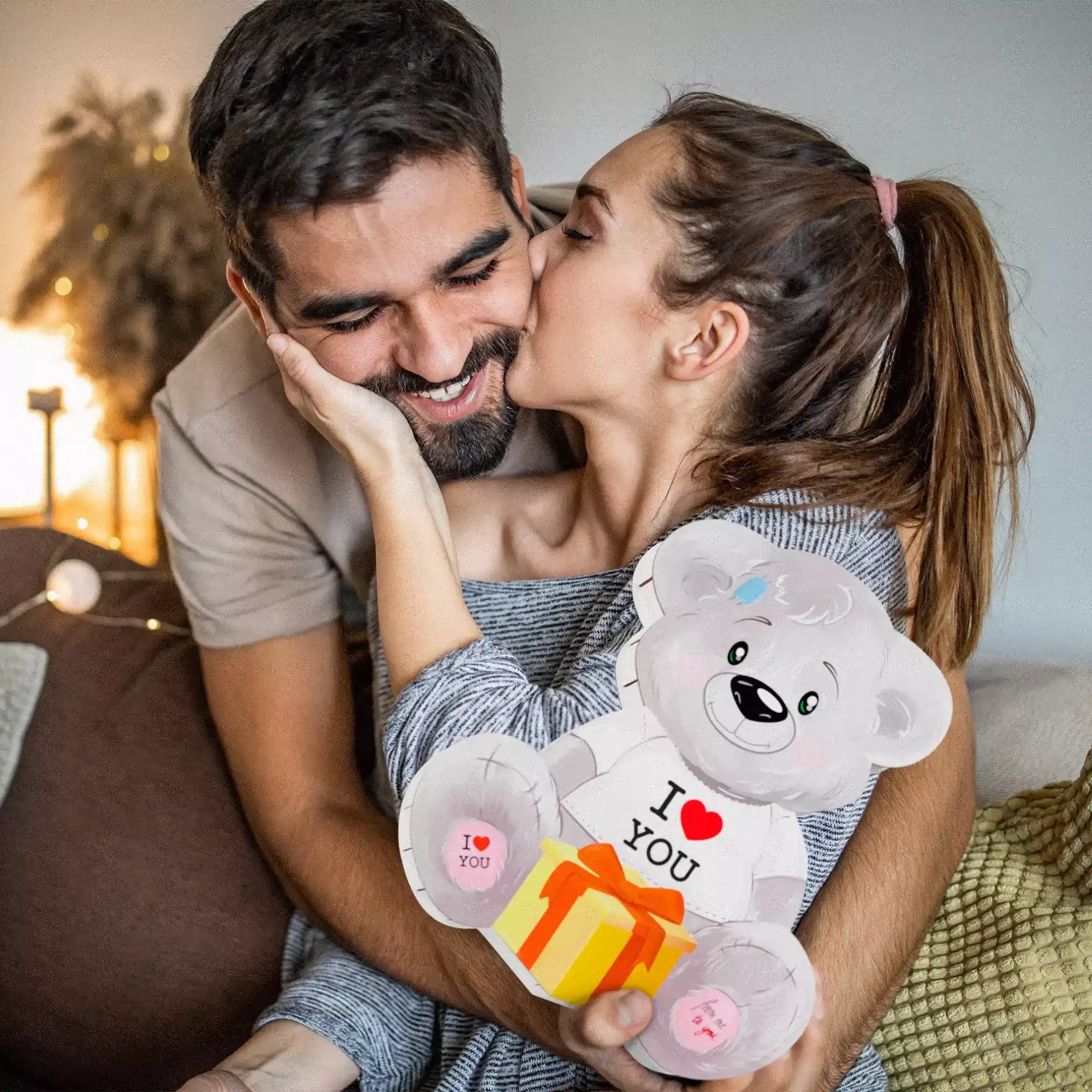 Paar kuschelt auf dem Sofa mit Teddybär-Geschenkbox – liebevolles Geschenk zum Valentinstag oder Jahrestag.