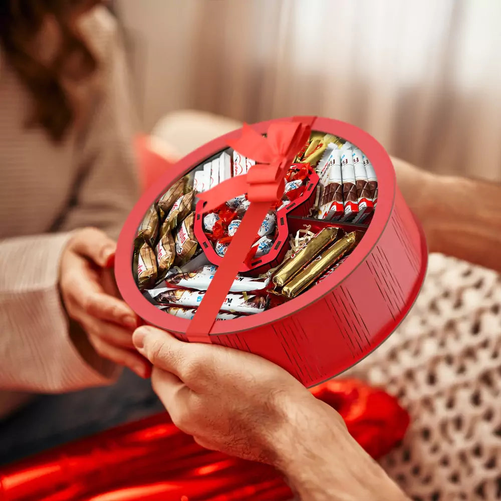 Person überreicht eine rote Geschenkbox mit Herzfach und Süßigkeiten – perfekte Geschenkidee für Partner, Freunde oder Familie.